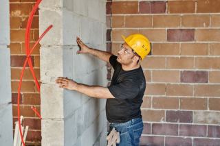 Photo d'illustration montrant un technicien examinant un mur avec un appareil